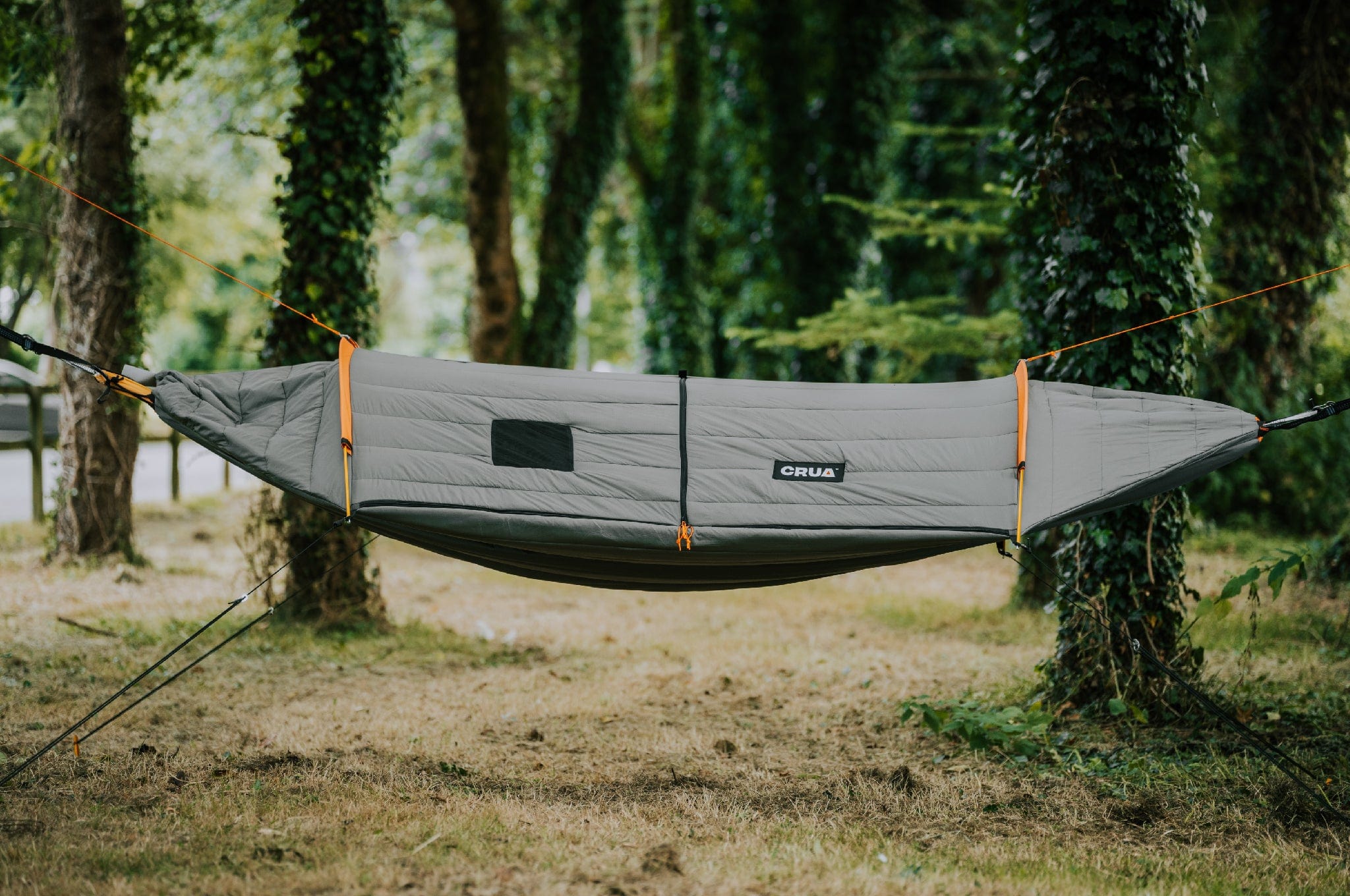 Crua Culla Hammock Wrap suspended between two trees with a forest background, showcasing its outdoor camping setup.