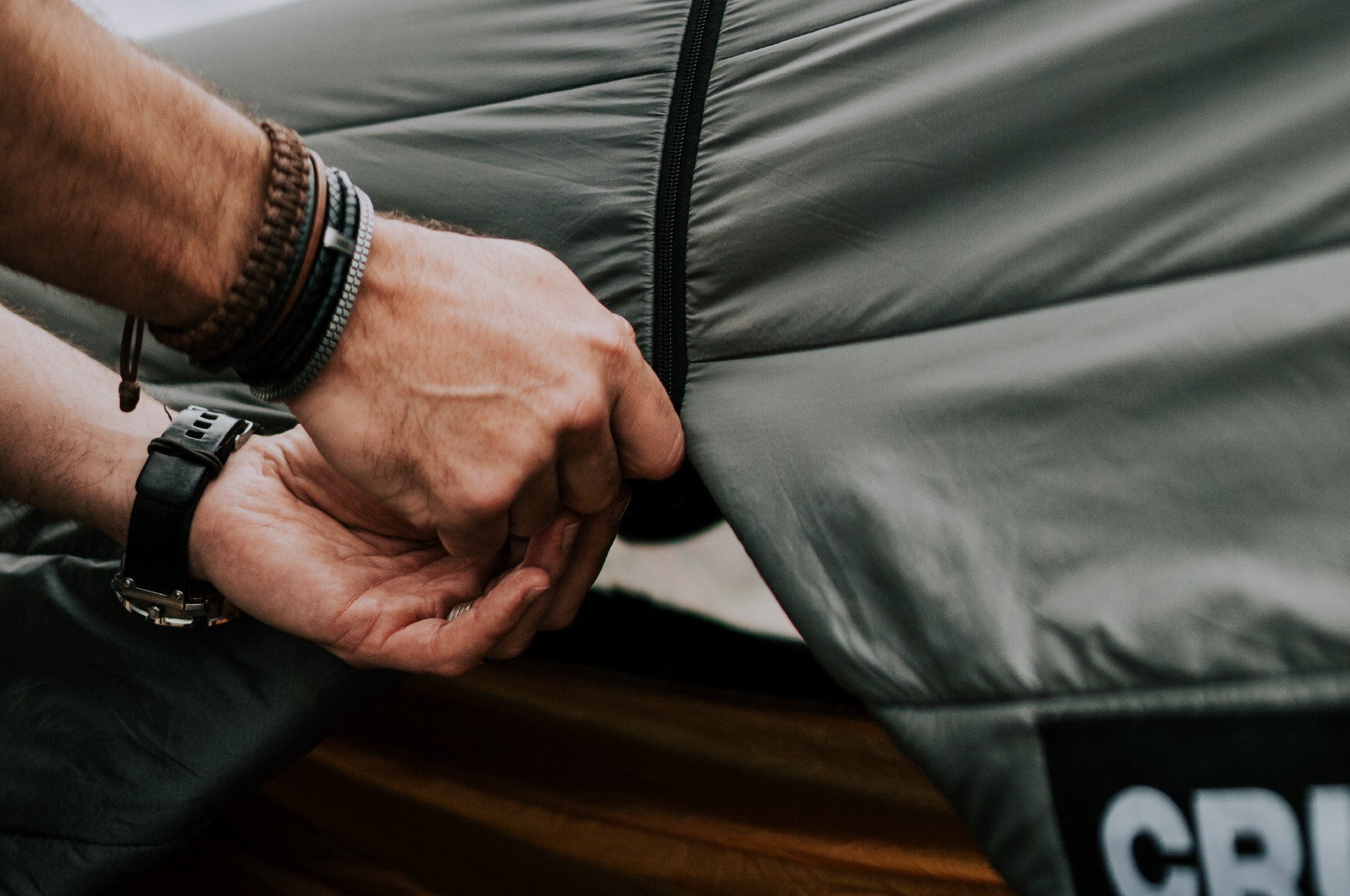 Close-up of someone’s hands opening the front door of the Crua Culla Hammock Wrap, illustrating ease of access.